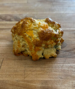 Golden-brown cheese biscuit resting on a wooden cutting board.