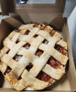 20260608_143642 | JustDane | Changing Lives. Changing the Community Lattice-crust fruit pie (likely cherry) in a cardboard takeout box, with coarse sugar on top.